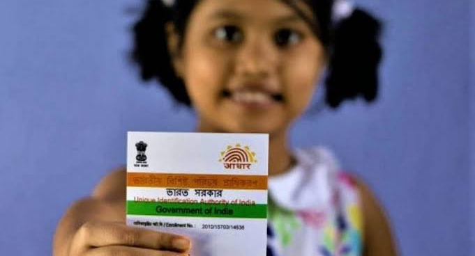A 4-5 year old girl holds Aadhaar card in her hand